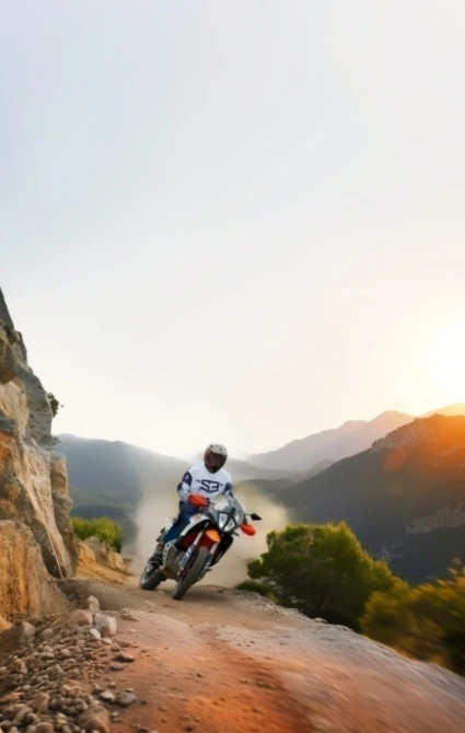 Rider on a KTM adventure bike on a rocky mountain trail at sunset in the Atlas