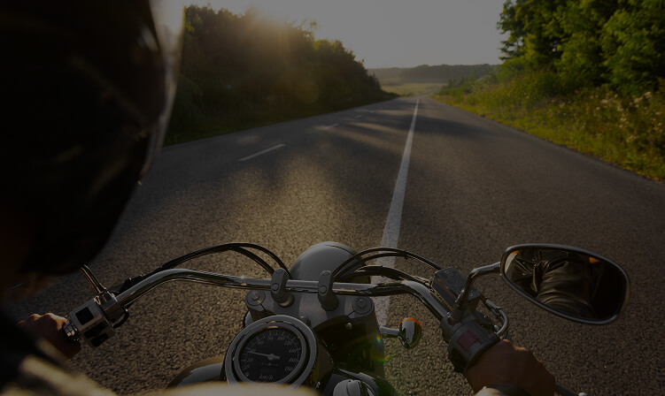 Rider's view over the handlebars on an empty road at sunset