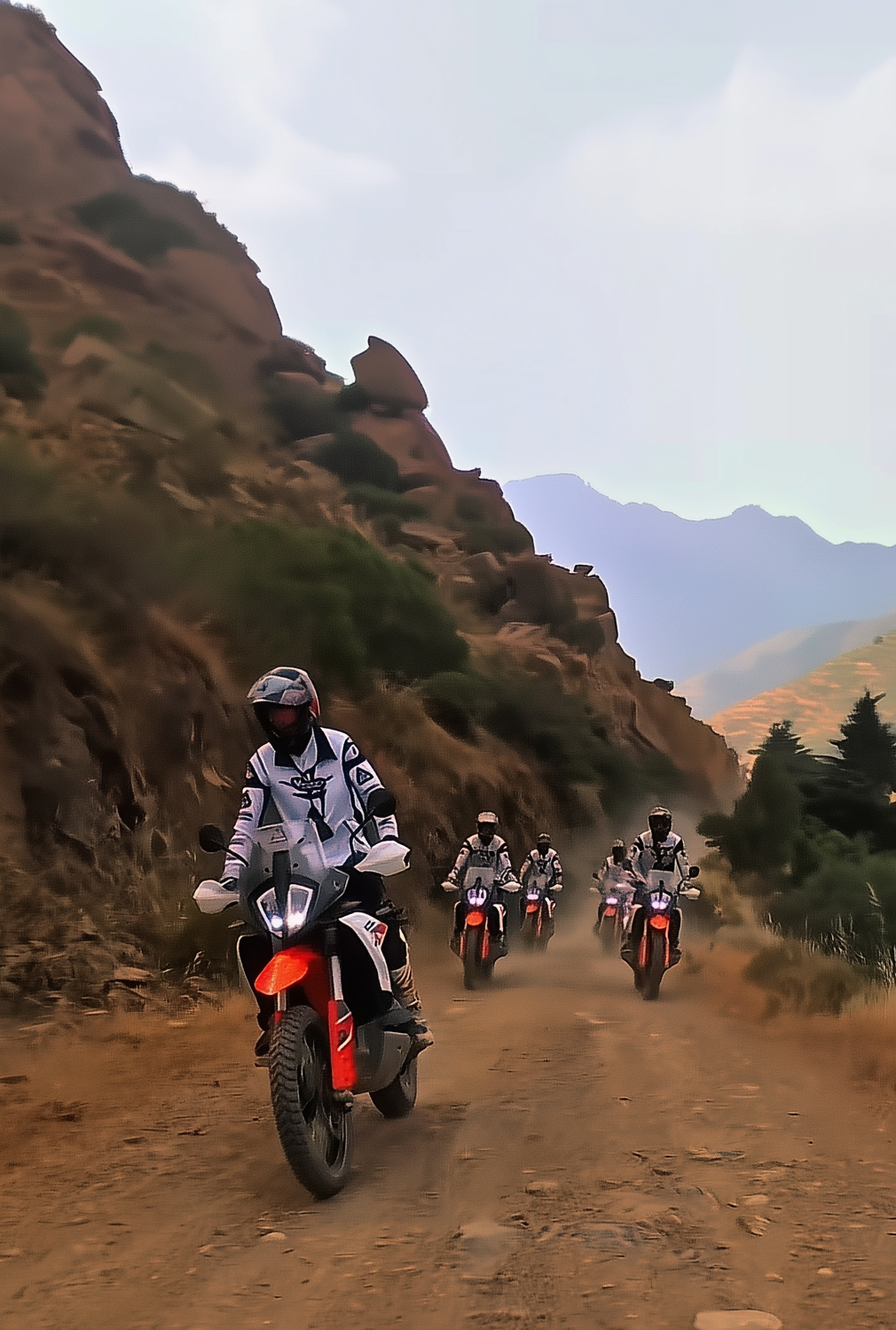Group of riders on KTM adventure bikes on a dirt track through a red rock canyon