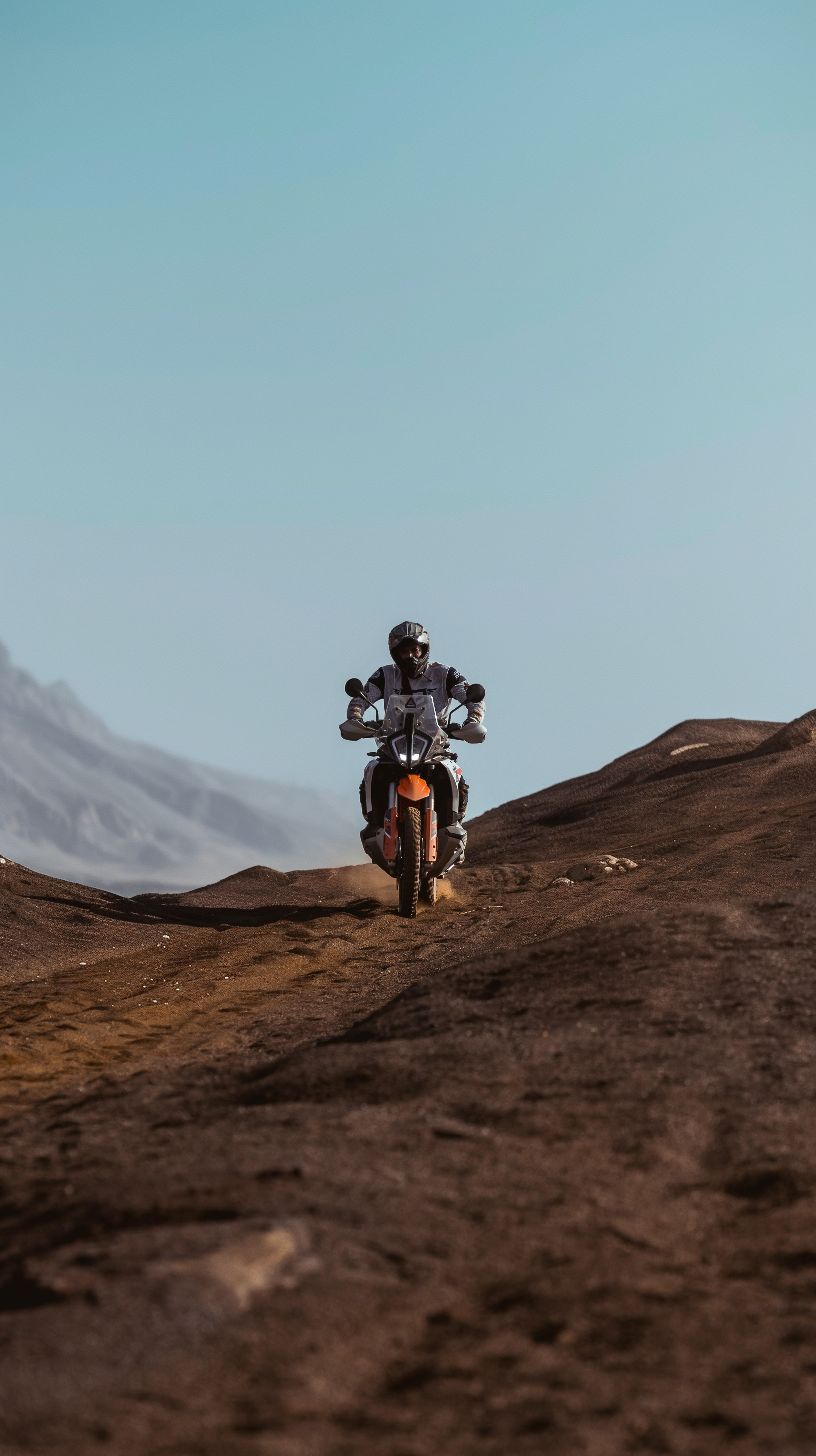 Rider on a KTM adventure bike coming over a rocky crest