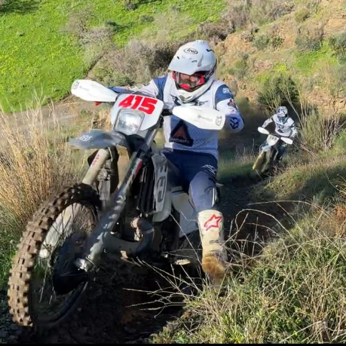 Enduro rider climbing a grassy hillside trail on the Mediterranean Enduro tour in Murcia