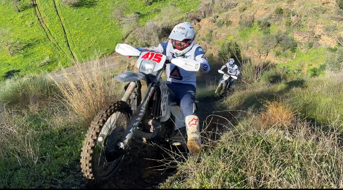 Enduro rider climbing a grassy hillside trail on the Mediterranean Enduro tour in Murcia