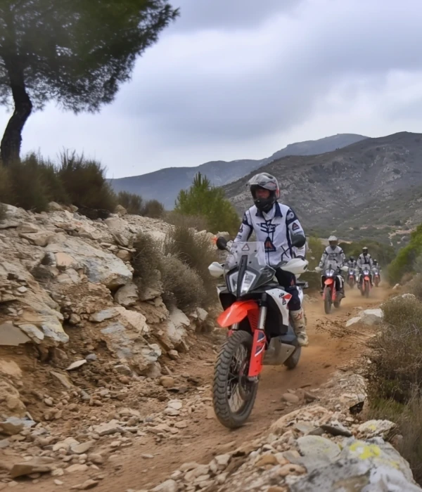 Group of riders on KTM adventure bikes on a rocky mountain trail