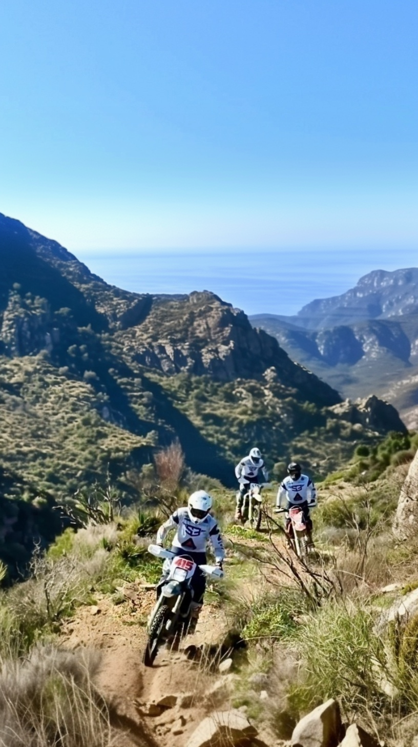 Enduro riders descending a mountain trail with sea views near Granada