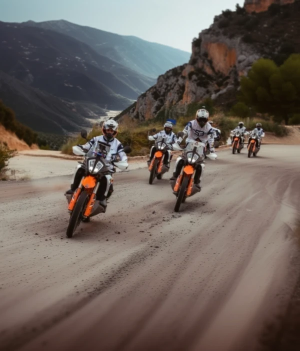 Group of riders on KTM adventure bikes on a mountain road through a rocky gorge in Andalusia