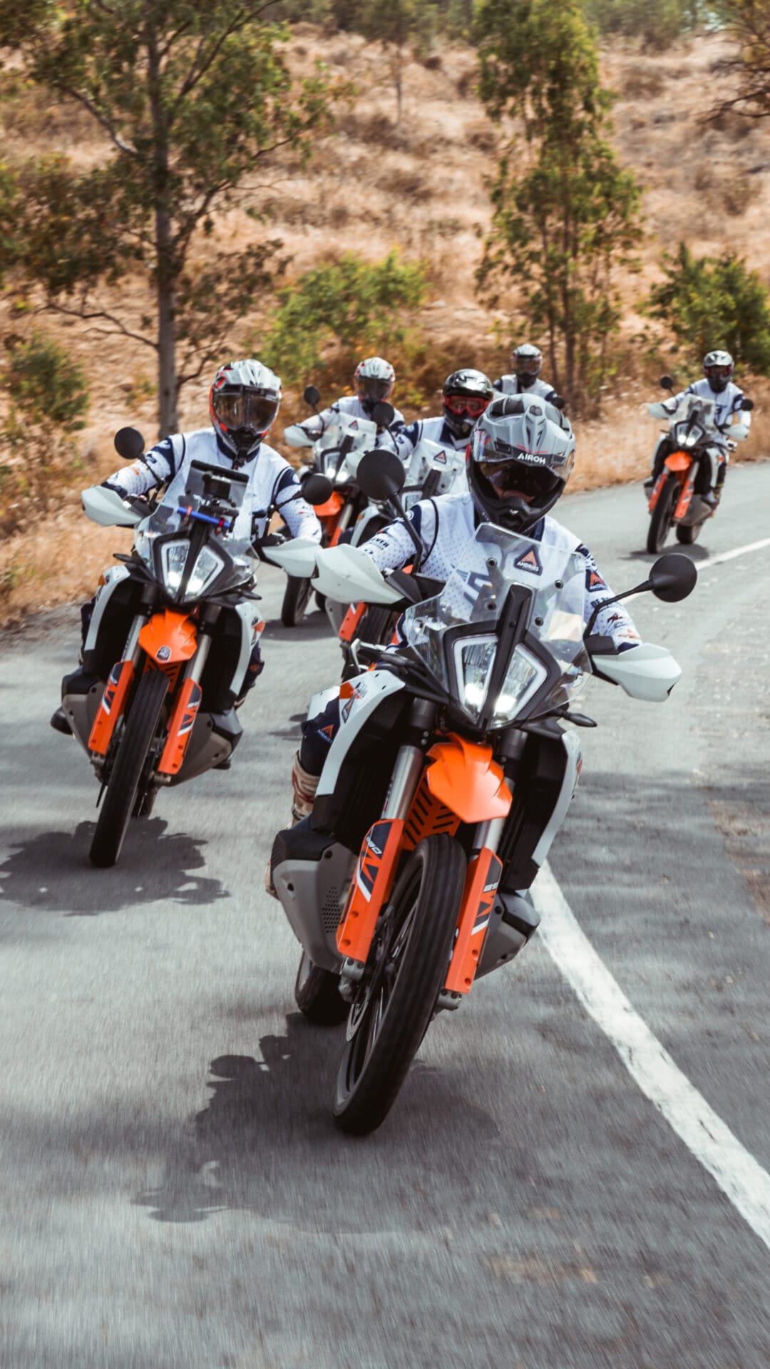 Group of riders on KTM adventure bikes on a winding asphalt road
