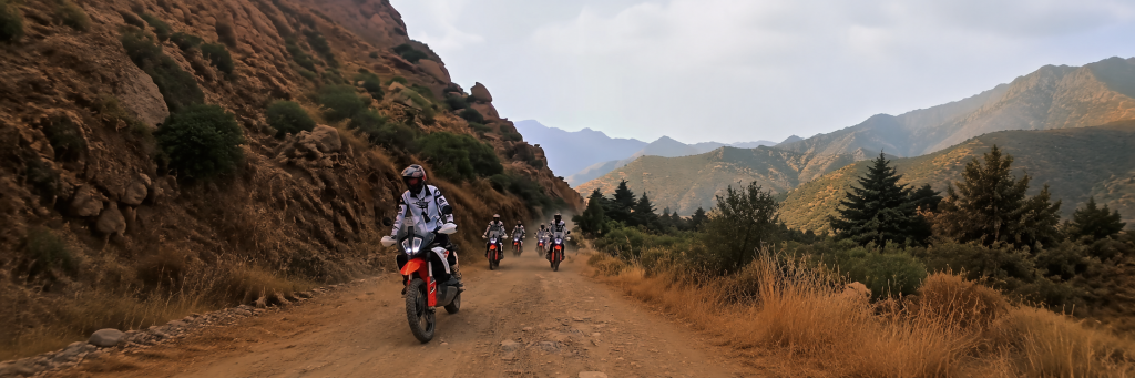 Riders on a dirt track through a mountain valley