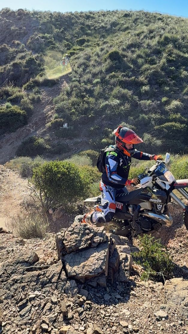 Enduro rider navigating a rocky trail in the green hills of Murcia