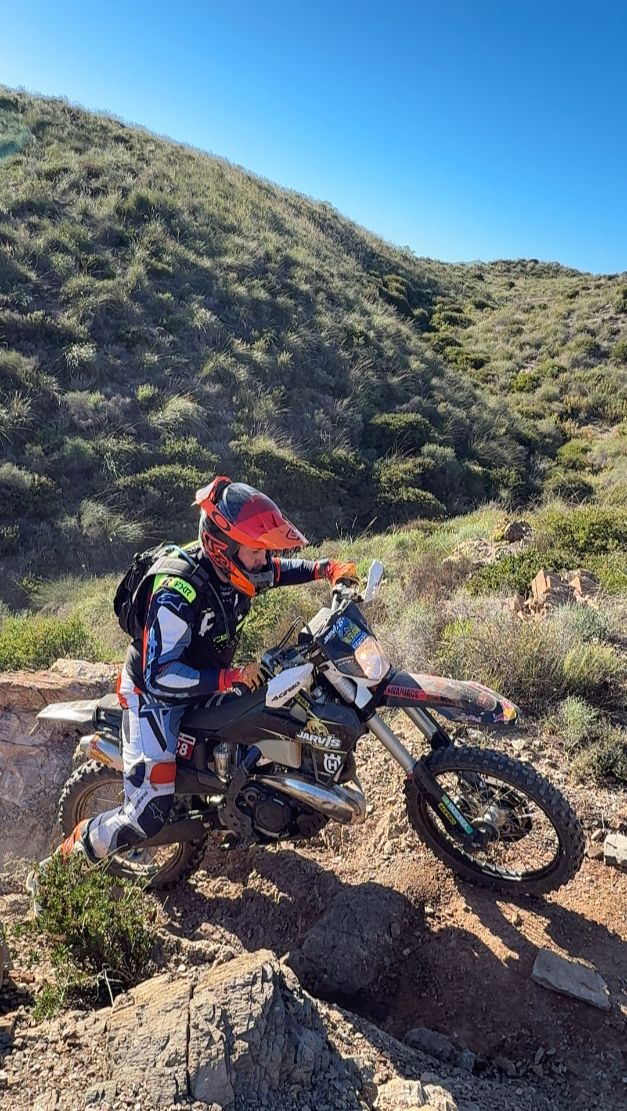 Enduro rider climbing a rocky step on a hillside trail