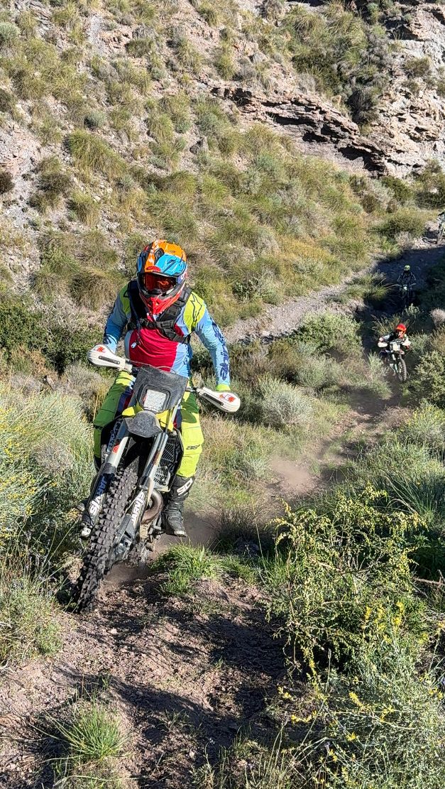 Enduro rider on a narrow singletrack through grassy hills near Lorca