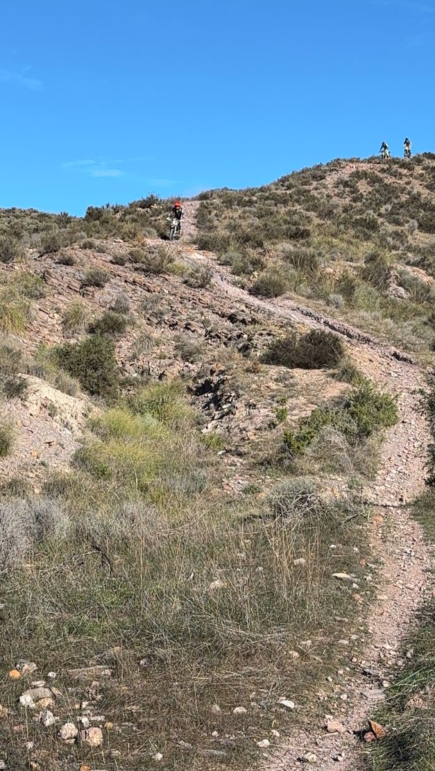 Singletrack climbing to a hilltop where enduro riders wait
