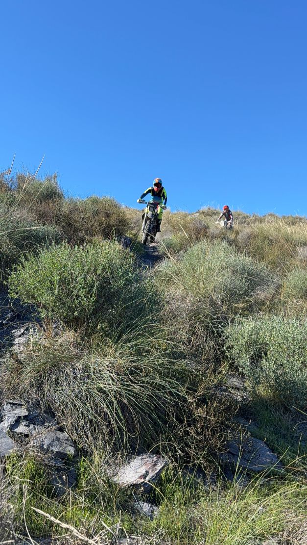 Enduro riders descending a grassy ridge trail in the mountains of southeast Spain