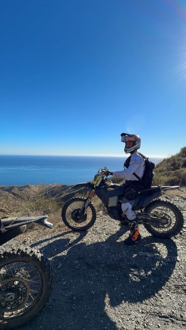 Enduro rider resting at a mountain viewpoint high above the Mediterranean