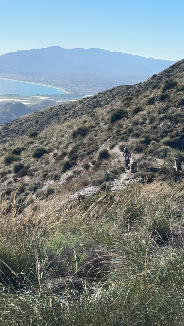 Enduro trail across a mountainside above a Mediterranean bay