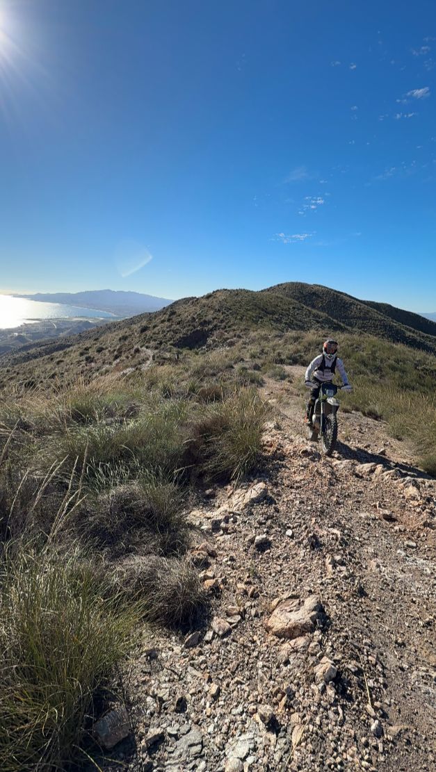 Enduro rider on a rocky ridge path high above the coast