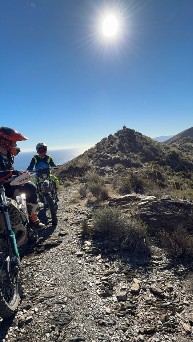 Enduro riders stopped on a rocky ridge trail above the sea