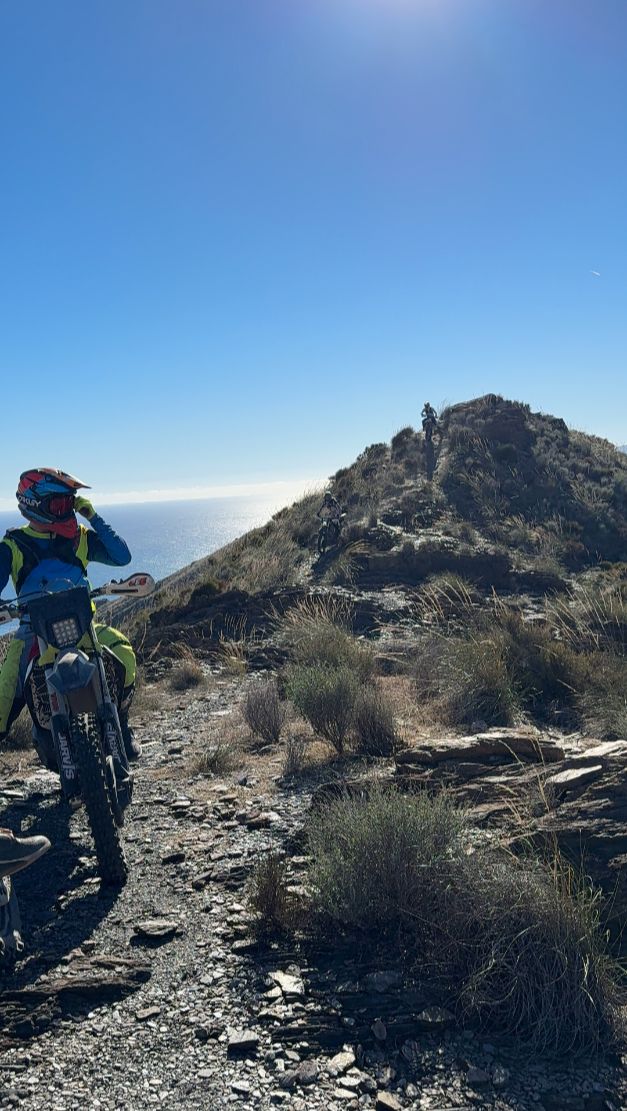 Enduro rider on a rocky summit ridge above the Mediterranean