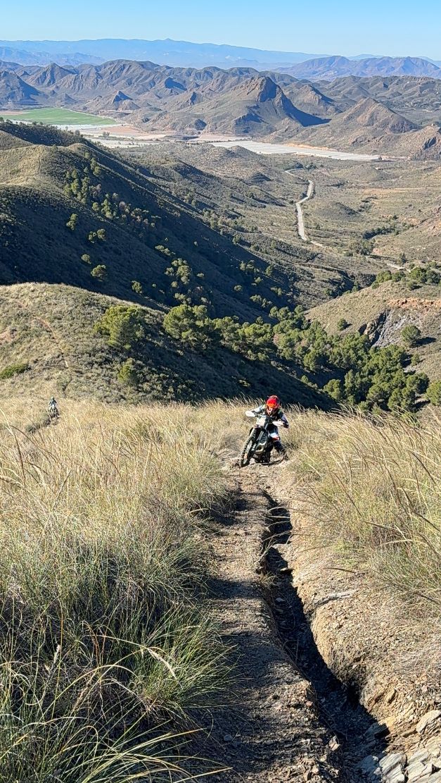 Enduro rider on a rutted singletrack high above a valley in Murcia