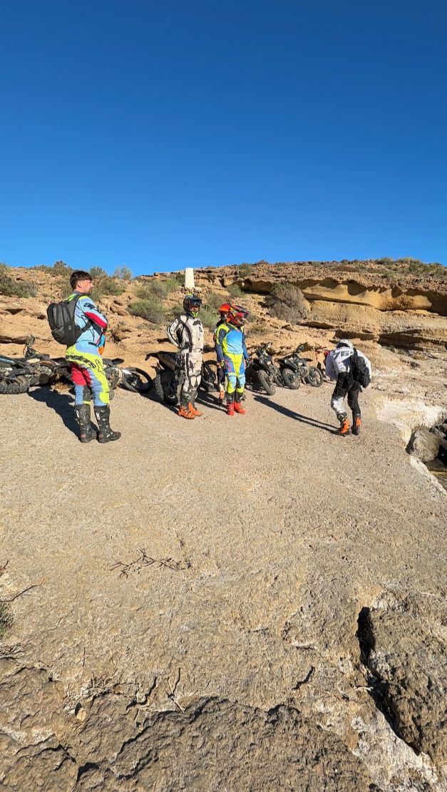 Enduro riders standing on a sandstone rock plateau on the coast