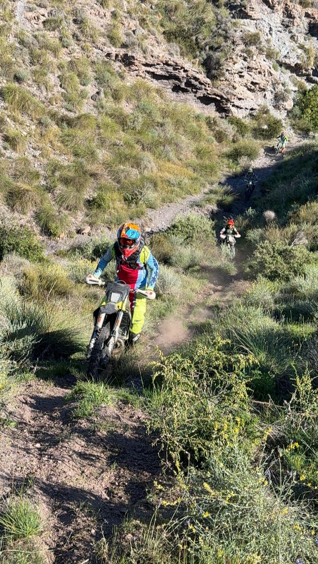Enduro rider on a rocky singletrack through green mountain scrub