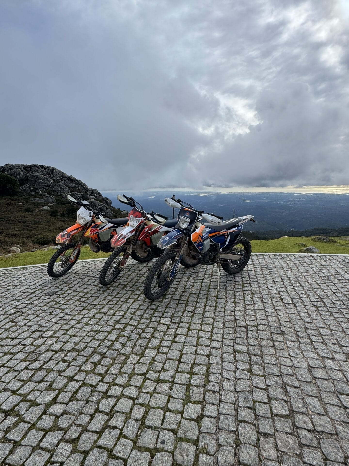 Three enduro motorcycles parked at a mountain viewpoint on the 500 km Enduro Tour in Spain