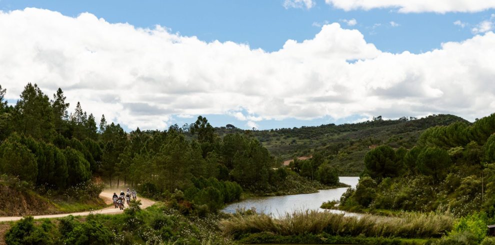 Riders on a track beside a winding river in the green hills of Portugal