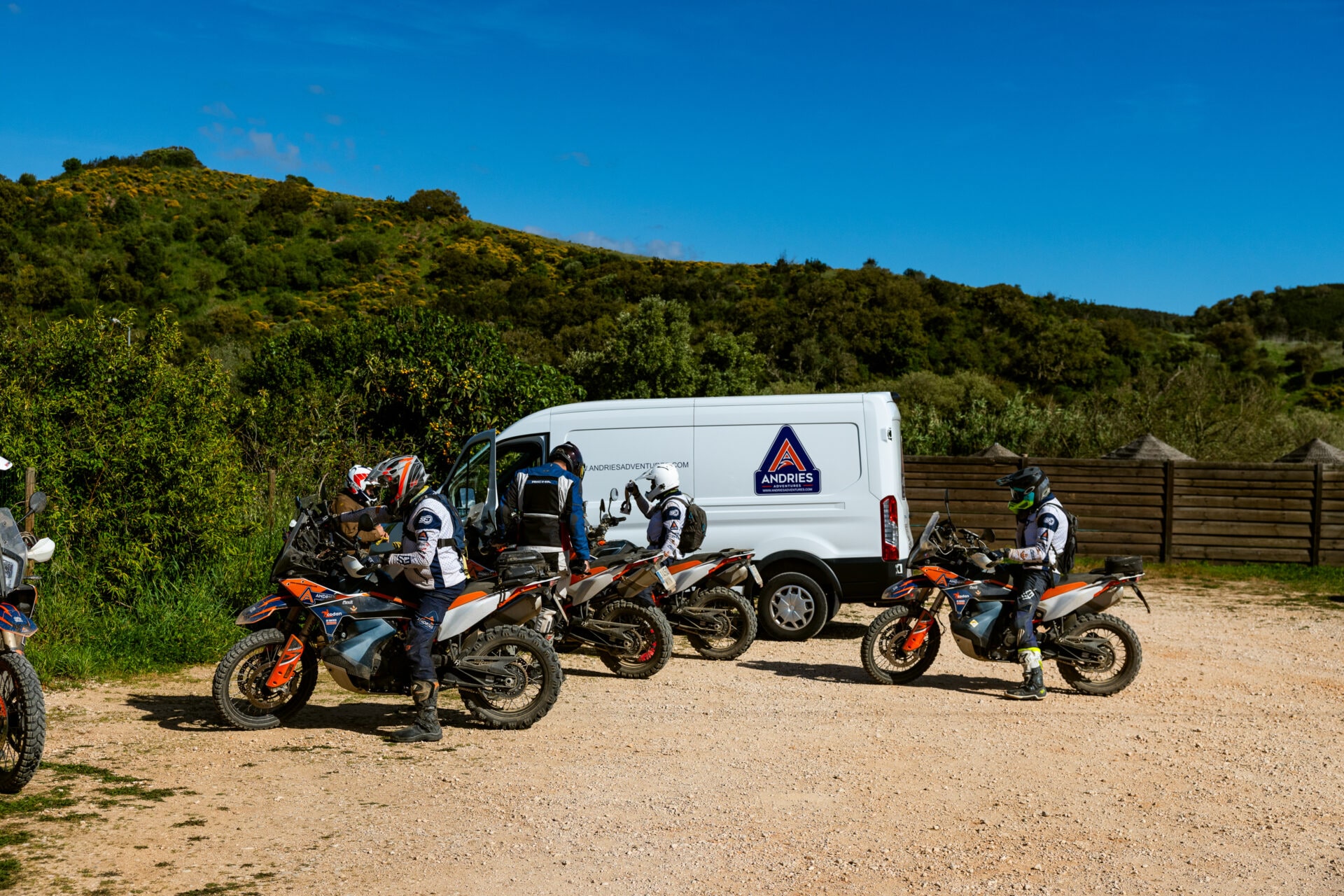 Riders and KTM adventure bikes at a rest stop next to the Andries Adventures support van