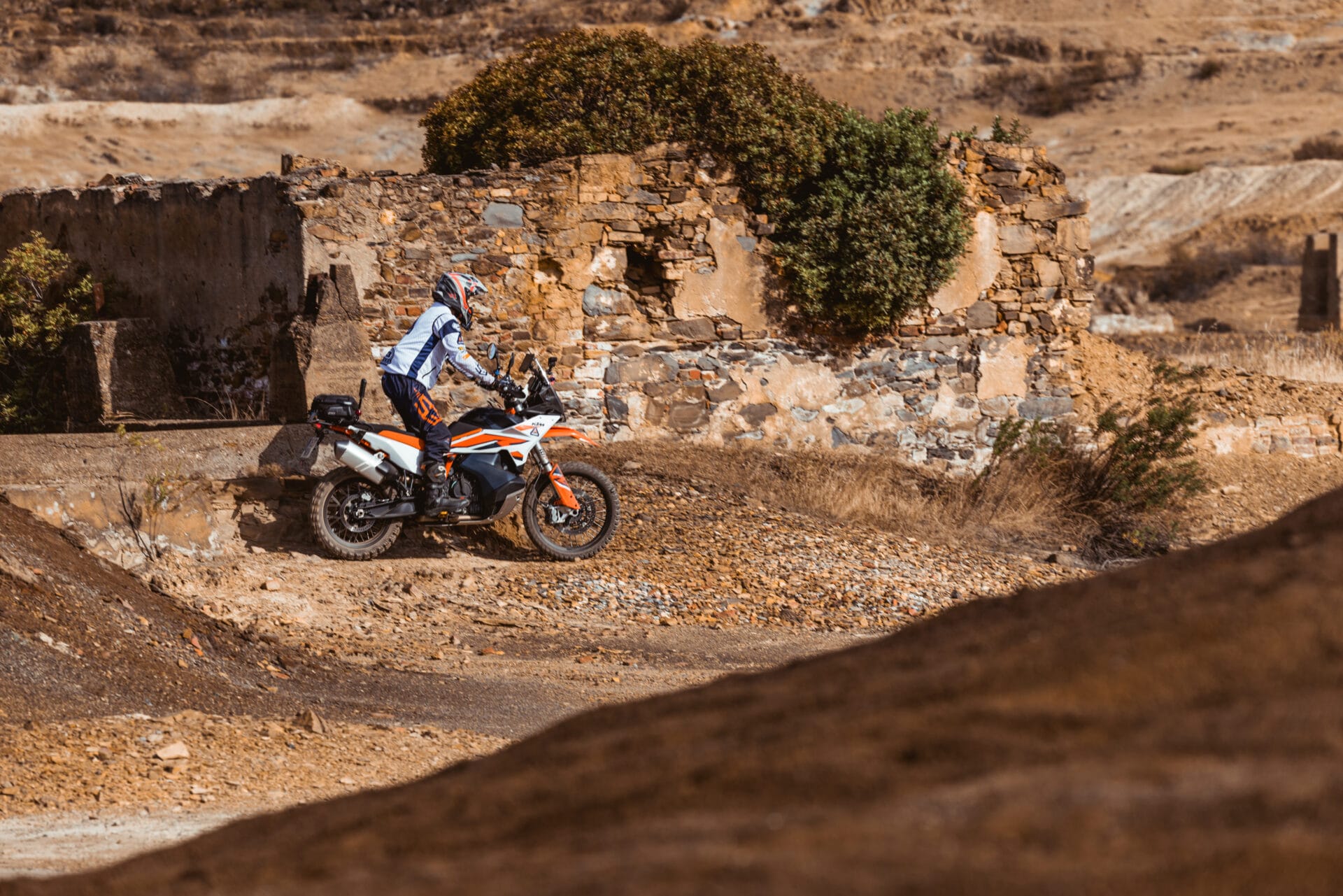 Rider on a KTM adventure bike among ruined mine buildings