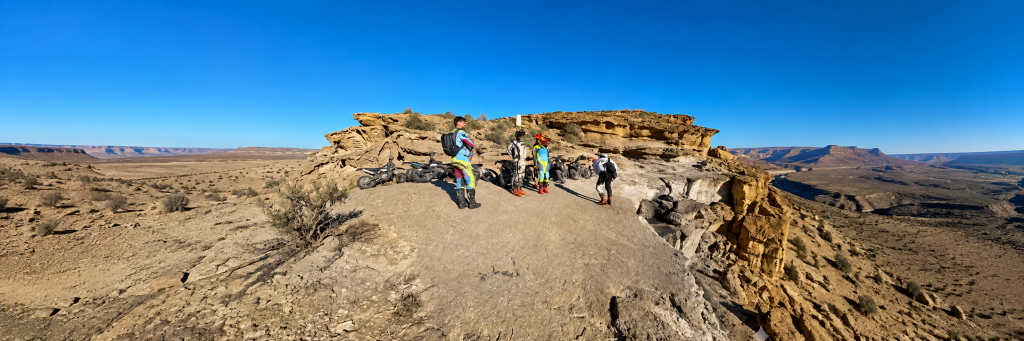 Motorcycle group resting on a rocky desert plateau during a guided tour