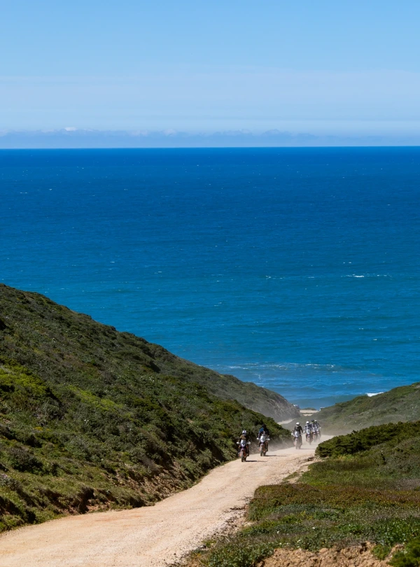 Riders on a dirt track leading down to the Atlantic Ocean in Portugal