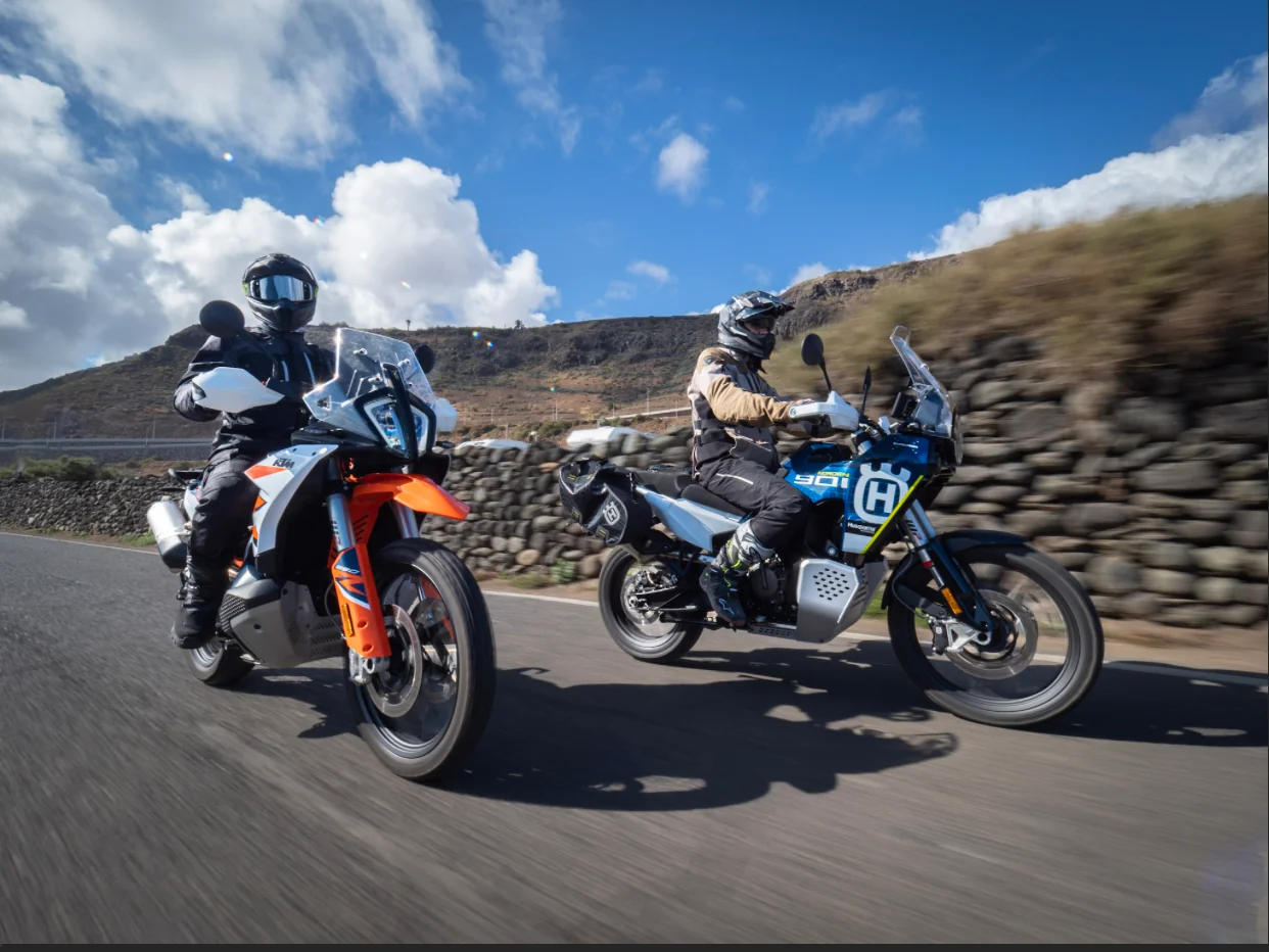 Two riders on adventure motorcycles on a road with lava stone walls in the Canary Islands