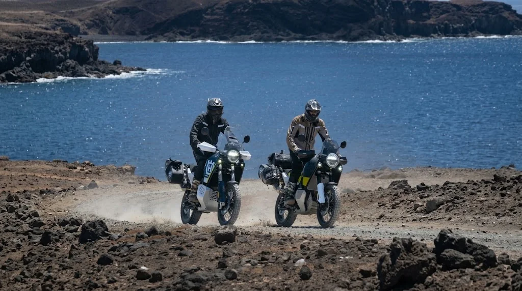 Two riders on adventure motorcycles on a volcanic coastal track in the Canary Islands