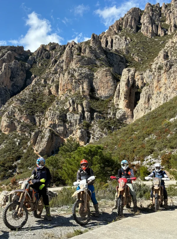 Enduro riders on dirt bikes below rocky limestone peaks in southern Spain