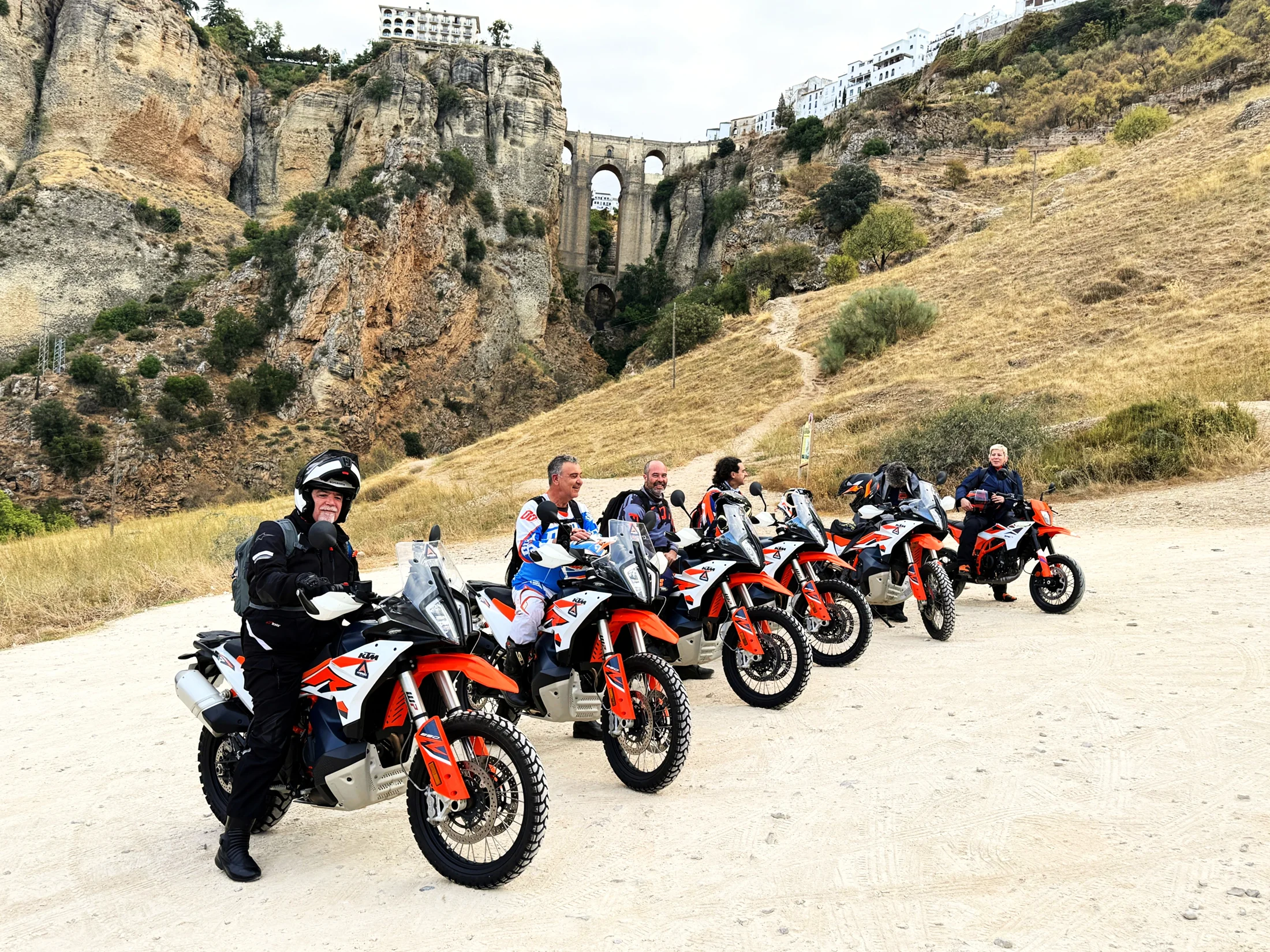 Group of riders with KTM adventure bikes below the Puente Nuevo bridge in Ronda