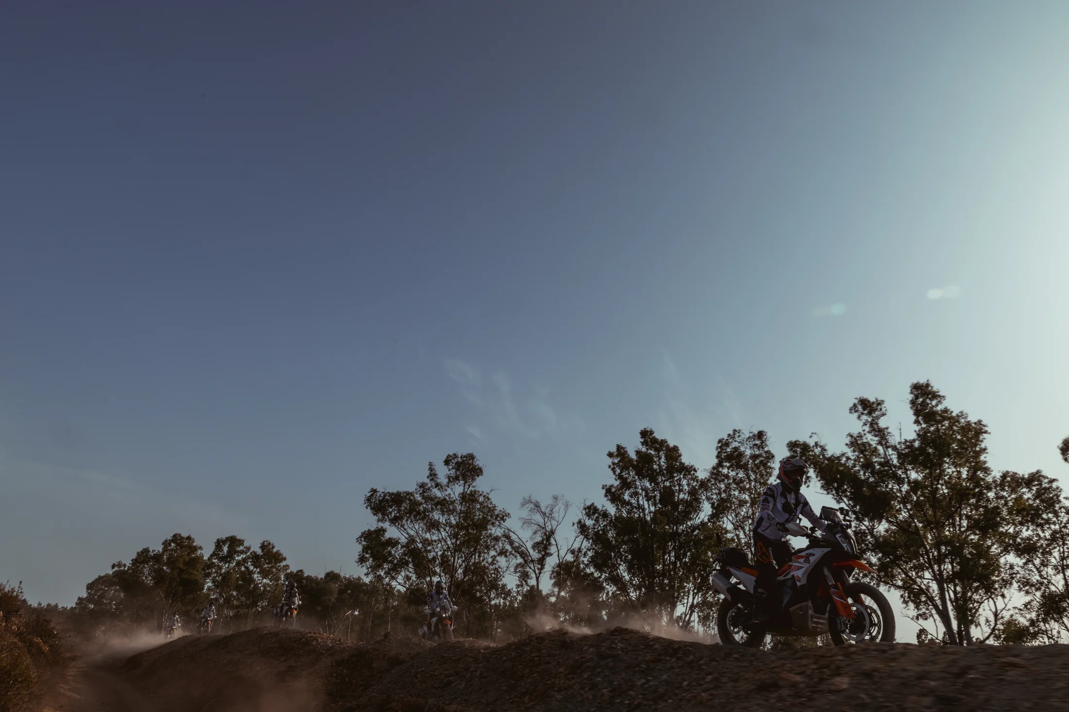 Silhouette of a rider on a KTM adventure bike on a ridge at dusk