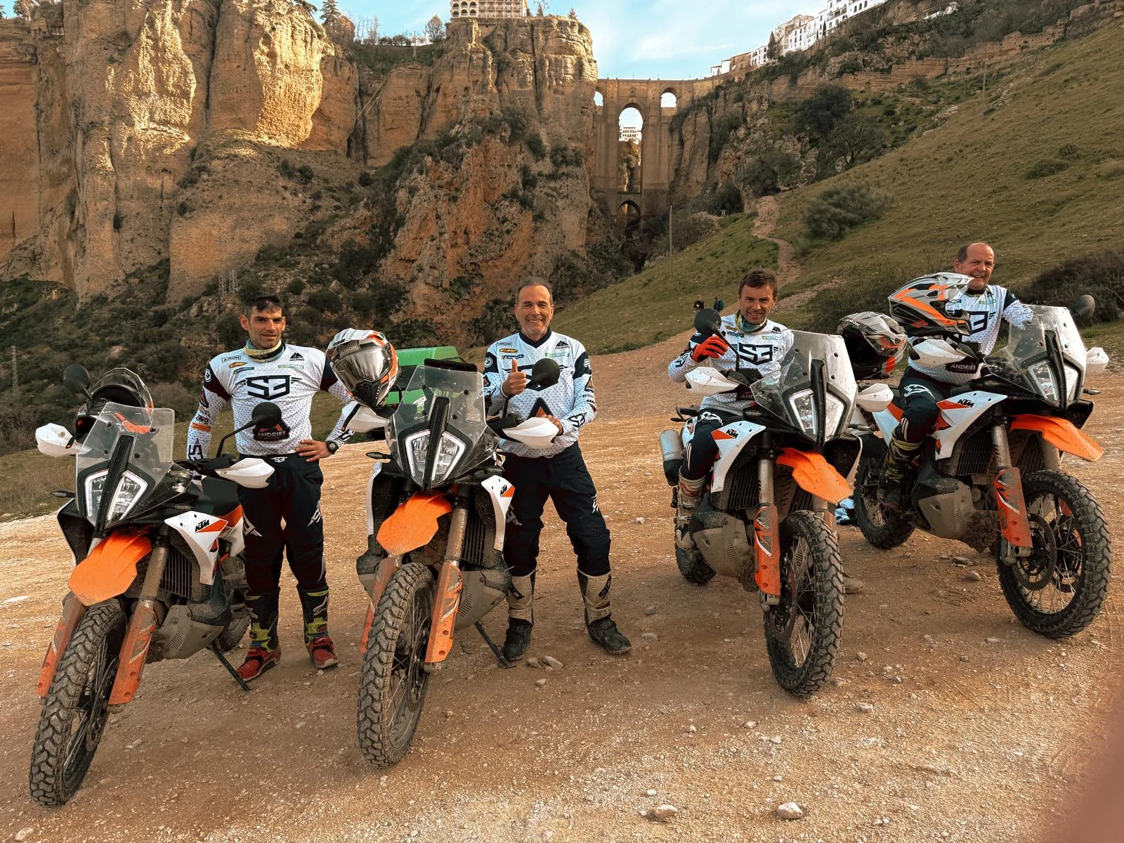 Riders posing with their KTM adventure bikes below the gorge and Puente Nuevo of Ronda