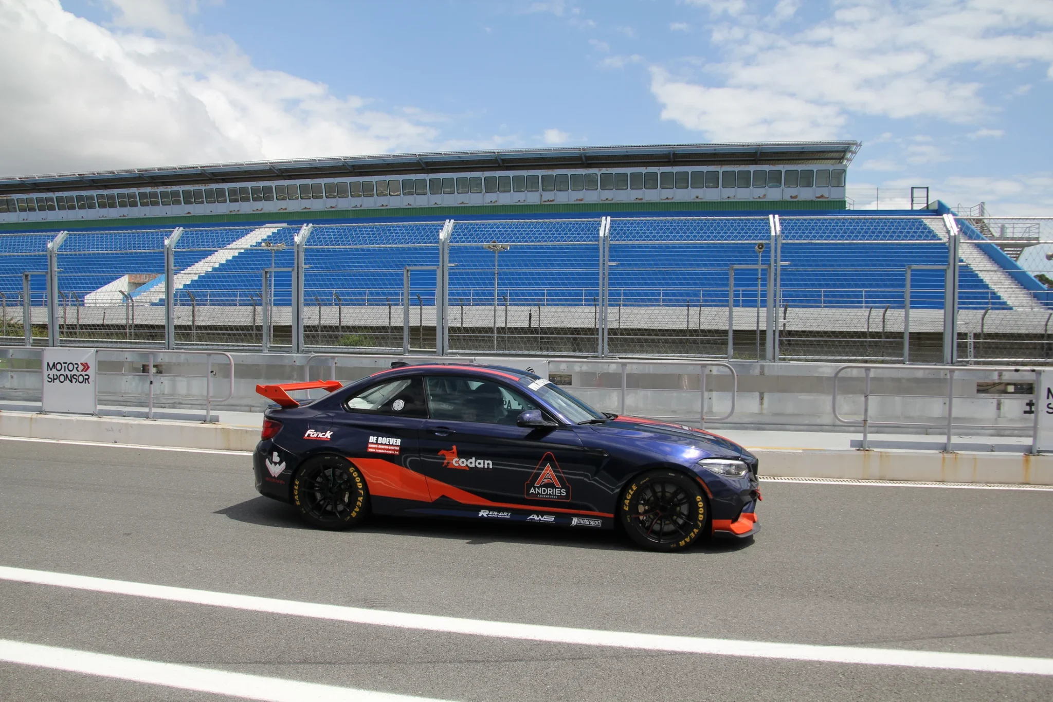 BMW M2 race car in Andries Adventures livery on the pit straight of a racing circuit